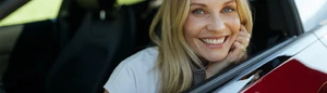 Blonde Frau im Auto lächelt in die Kamera