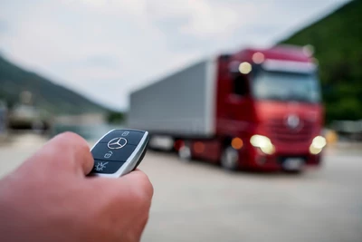 Mercedes-Benz Actros Schlüssel und roter LKW im Hintergrund
