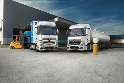 zwei Mercedes Benz Actros werden in einem Logistikcenter beladen von Gabelstaplern