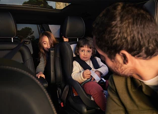 Familie sitz in Mercedes-Benz EQV Van Vater schaut nach hinten zu den Kindern