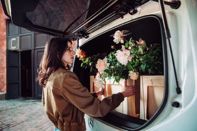 Frau läd Blumen aus einer Mercedes-Benz V-Klasse