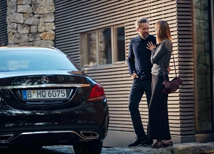 Frau und Mann stehen glücklich vor ihrem Mercedes