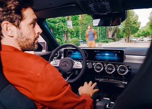 Mann in rot sitz auf Fahrersitz eines Mercedes