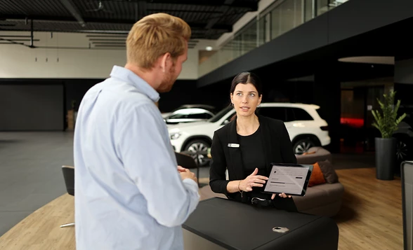 Kunde wird von einer Mitarbeiterin beraten im Mercedes Benz Autohaus