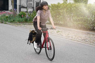 Frau mit Helm fährt URWAHN E-Bike Stadtfuchs in rot